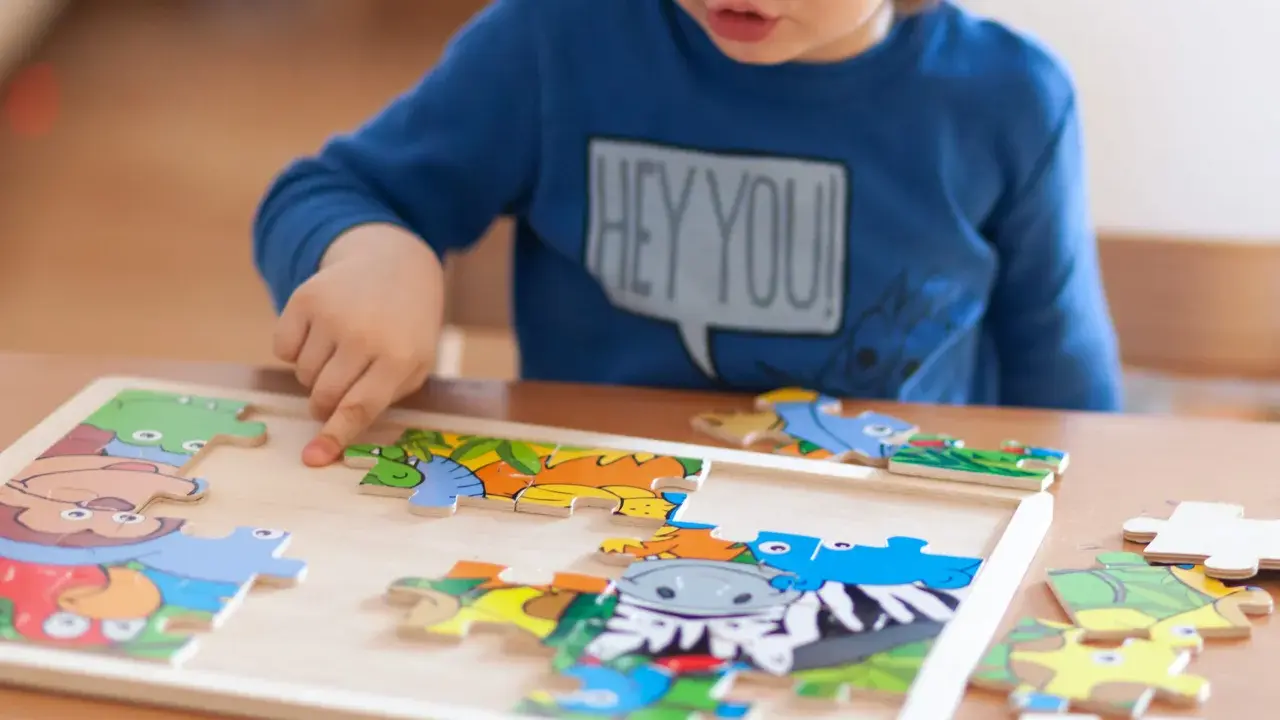 Chłopiec układa kolorowe puzzle ze zwierzątkami. Ukladanie puzzli co ćwiczy? Rozwija spostrzegawczość i zdolności manualne.
