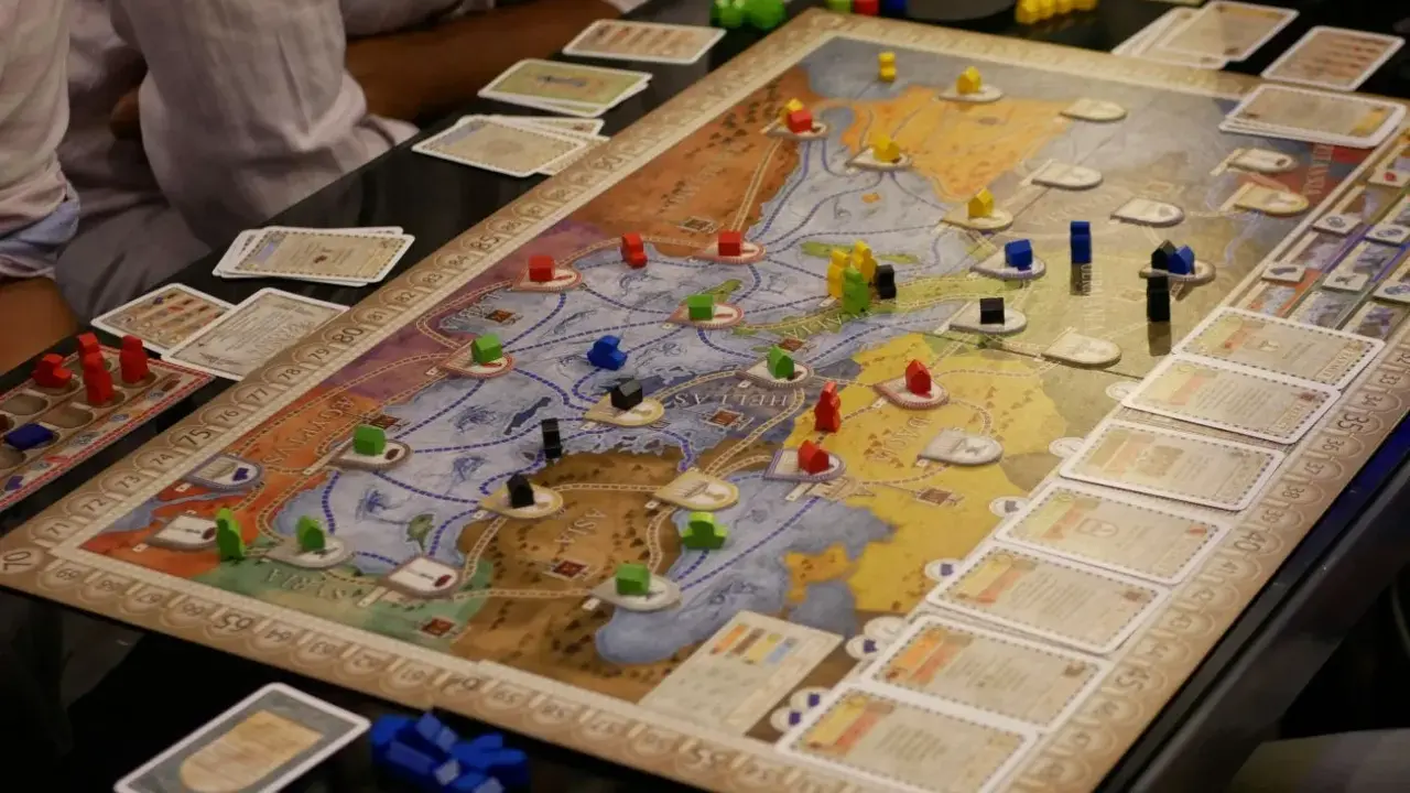 Intensywne granie w gry planszowe. Gracze strategicznie rozmieszczają drewniane pionki na mapie, budując imperium.