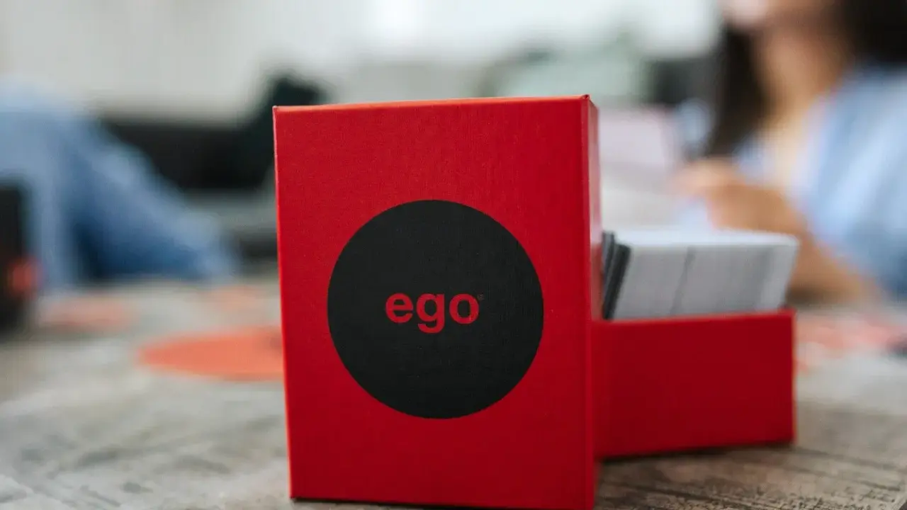 Czerwone pudełko gry "ego" z czarnym kołem i napisem "ego" w środku. Obok stos kart. Czas na ego gold pytania!