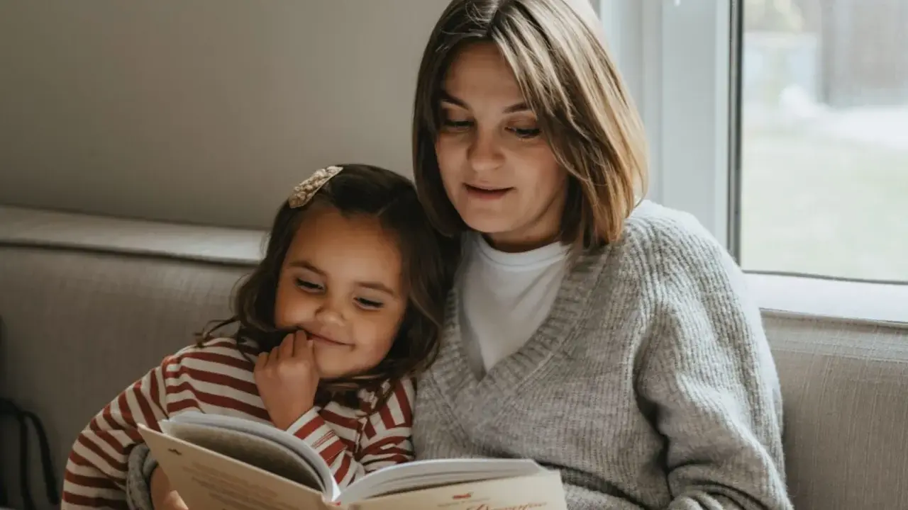 Mama czyta dziecku bajkę, pokazując, jak zachęcić dziecko do czytania. Wspólne chwile z książką budują więź i rozwijają wyobraźnię.