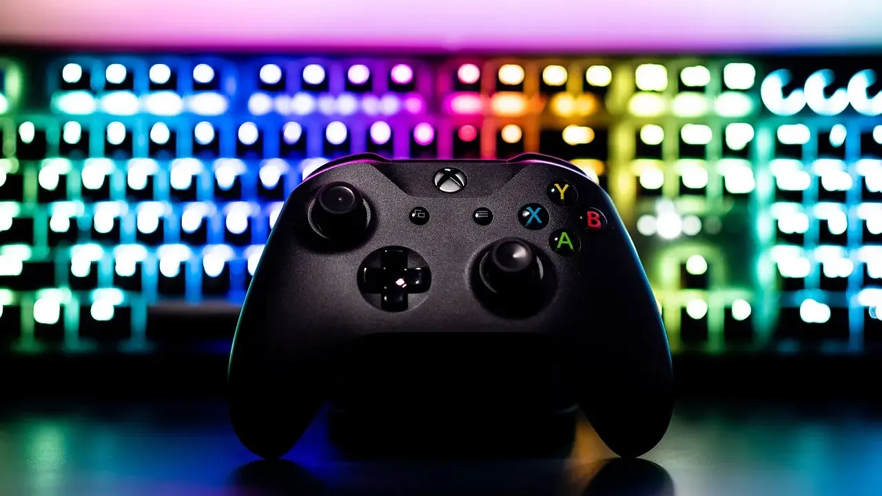 Czarny kontroler Xbox na tle podświetlanej klawiatury RGB. Idealny sprzęt do **grania na długie godziny**.