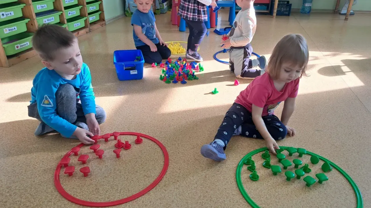 Dzieci w przedszkolu bawią się klockami, tworząc wzory w obręczach. To świetne zabawy dla 3 latka w przedszkolu.