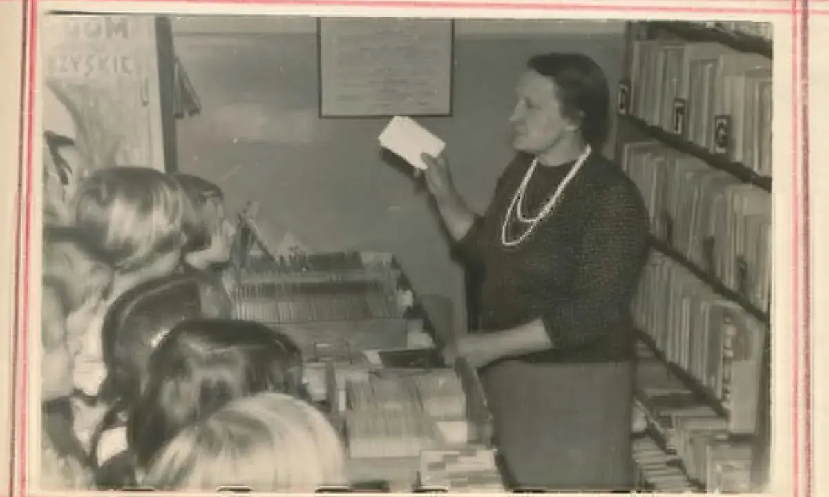Nauczycielka w bibliotece, jak siłaczka, prezentuje dzieciom karty. Streszczenie lekcji w formie kart.