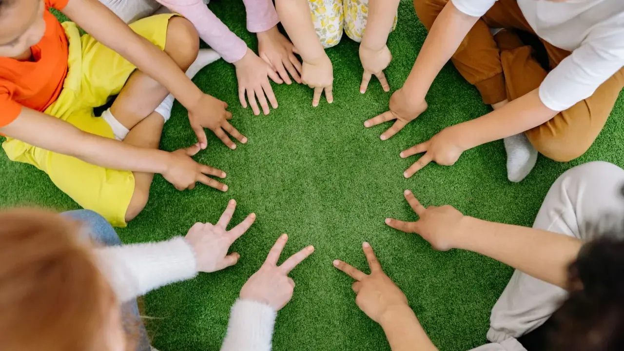 Dzieci tworzą krąg, pokazując palcami cyfry. To spokojne zabawy wyciszające Montessori, rozwijające koncentrację i współpracę.