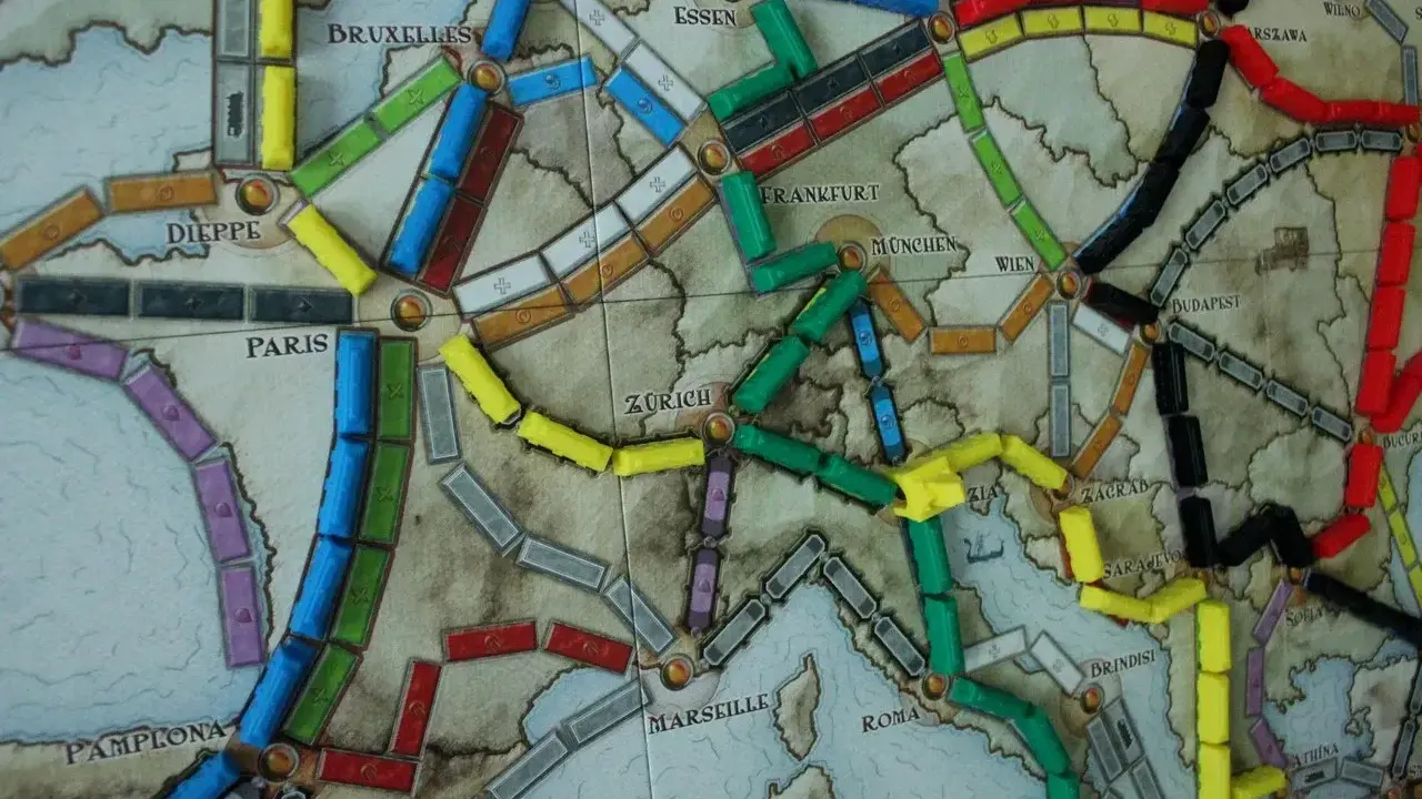 Planszowa mapa Europy z kolorowymi wagonikami. Która trasa jest najlepsza, by wsiąść do pociągu i odkryć nowe miasta?
