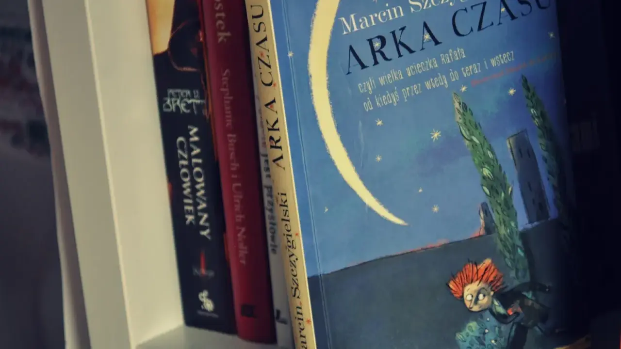 Książka "Arka Czasu" Marcina Szczygielskiego na półce. Ilustracja przedstawia nocne niebo z księżycem i biegnącą postacią.