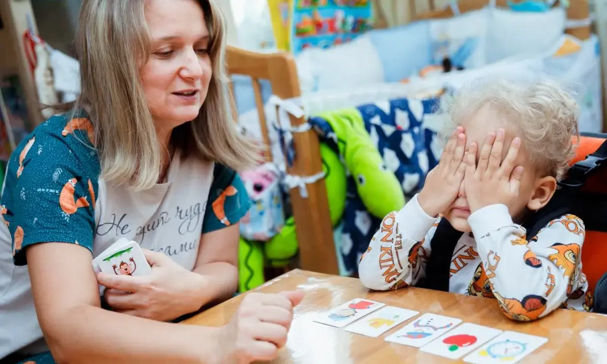 Kreatywne zabawy dla dzieci w wieku szkolnym: mama z synkiem grają w memory, rozwijając pamięć i spostrzegawczość.