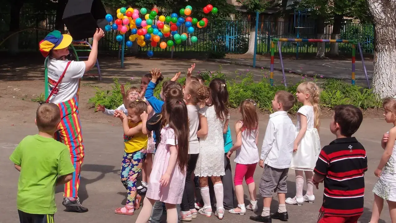 Animator wypuszcza balony, dzieci łapią je z radością. Świetny pomysł na urodziny dla dzieci na świeżym powietrzu!