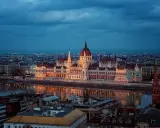 Budynek Parlamentu w Budapeszcie nocą, odbijający się w Dunaju. Miasto tętni życiem, aspirując do miana najbardziej imprezowych miast w Europie.