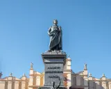 Pomnik Mickiewicza, symbol romantyczności, na tle Sukiennic. Streszczenie epoki w kamieniu i architekturze.