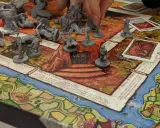 Gra planszowa RPG dla początkujących z figurkami i kartami. Gracze poruszają pionkami po planszy, walcząc i zdobywając przedmioty.