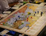 Intensywne granie w gry planszowe. Gracze strategicznie rozmieszczają drewniane pionki na mapie, budując imperium.