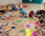 Dzieci biorą udział w zabawach animacyjnych, rysując na kolorowych kartkach.