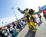 Bumblebee wita fanów na Pyrkonie. Tłum ludzi w kostiumach i z torbami idzie chodnikiem.
