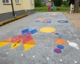 Kolorowe gry plenerowe na placu zabaw: rakieta z liczbami, układ planet i plansza do gry.
