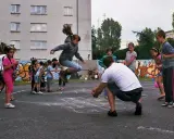 Dzieci skaczą przez skakankę, grając w szczura. Jedna dziewczynka jest w powietrzu, a inni czekają na swoją kolej.