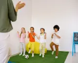 Dzieci ćwiczą przy tablicy z napisem "Sport time". Krótkie hasła sportowe dla dzieci motywują do ruchu.