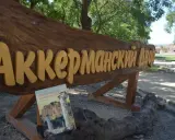 Drewniany napis "Аккерманский Двор" i książka "Sonety Krymskie" na tle stepów akermanskich i ruin.