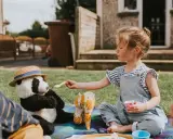 Dziewczynka karmi pluszową pandę na pikniku. Świetny sposób, co robić na nudę w ogrodzie!