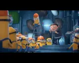 Gru przemawia do grupy minionków, które pracują w laboratorium. Widać różne minionki części, niektóre w kaskach.