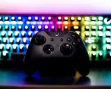 Czarny kontroler Xbox na tle podświetlanej klawiatury RGB. Idealny sprzęt do **grania na długie godziny**.