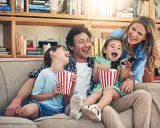 Rodzina śmieje się do rozpuku, jedząc popcorn podczas oglądania filmu dla całej rodziny.