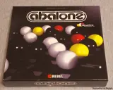Gra Abalone Quattro, strategiczna gra w 5 kulek, z kulami w kolorach białym, żółtym i czarnym.