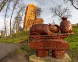 Drewniane rzeźby zająca i sakiewki nawiązują do legendy o Popielu. W tle ceglana wieża i ruiny zamku.