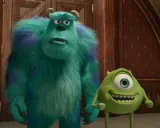 Sully i Mike, bohaterowie bajek z 4 postaciami, stoją obok siebie. Sully wygląda na zmartwionego, a Mike uśmiecha się szeroko.