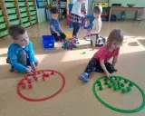 Dzieci w przedszkolu bawią się klockami, tworząc wzory w obręczach. To świetne zabawy dla 3 latka w przedszkolu.