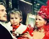 Rodzina w bogatych strojach, ojciec trzyma dziecko. Scena z filmu "Ziemia obiecana" streszczenie.
