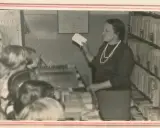 Nauczycielka w bibliotece, jak siłaczka, prezentuje dzieciom karty. Streszczenie lekcji w formie kart.