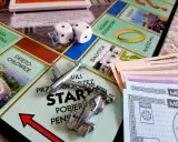 Gra Monopoly, kostki, pionki (samolot, bolid), pieniądze i plansza z polskimi miastami. Różne rodzaje gry wciągają graczy w świat finansów.