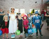 Dzieci w strojach na Halloween, gotowe na psikusy i zbieranie słodyczy. Wśród nich księżniczka, Kapitan Ameryka i inne postacie.