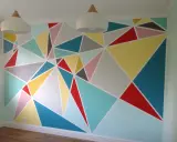 Kolorowe malunki na ścianie dla dzieci w geometryczne wzory. Radosna, pastelowa paleta barw tworzy wesołą atmosferę.