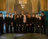 Grupa uczniów z domu Hufflepuff, w tym Harry Potter, stoi w eleganckiej sali.