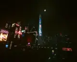 Mroczna, neonowa nocna miasto, pełne reklam i wieżowców. Księżyc w pełni oświetla futurystyczny krajobraz.