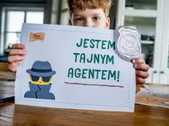 Chłopiec trzyma kartkę z napisem "Jestem tajnym agentem!" i odznaką. Idealne do gier escape room.
