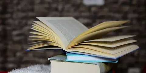 Otwarta książka na stosie innych, jakby zapraszała do przygody w stylu escape room.