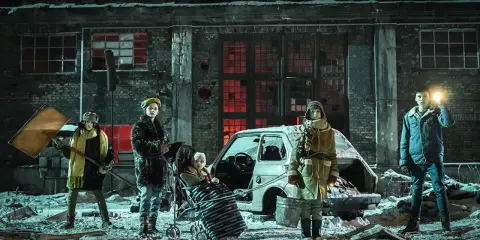Dzieci w zimowej scenerii, przy zniszczonym samochodzie i fabryce. To streszczenie "Czarnego młyna" - opowieści o przetrwaniu.
