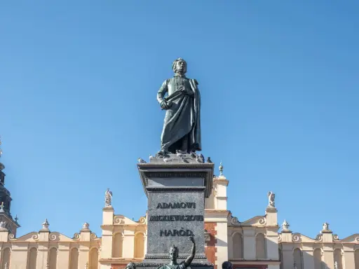 Pomnik Mickiewicza, symbol romantyczności, na tle Sukiennic. Streszczenie epoki w kamieniu i architekturze.