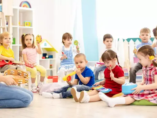 Wesołe zabawy w przedszkolu: dzieci grają na instrumentach, śpiewają i bawią się w rytm muzyki.
