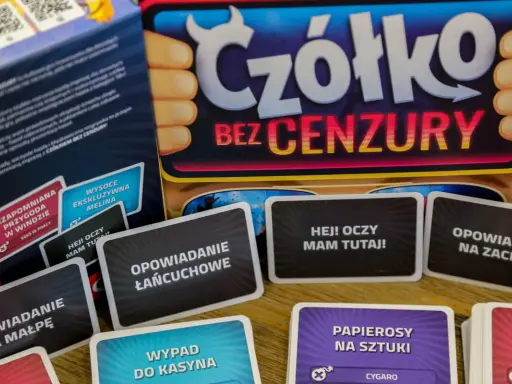 Karty do gry "Czółko bez cenzury" leżą na stole. Widać napisy: "Opowiadanie łańcuchowe", "Hej! Oczy mam tutaj!", "Opowiadanie na małpę", "Wypad do kasyna".