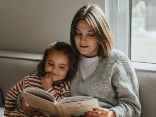 Mama czyta dziecku bajkę, pokazując, jak zachęcić dziecko do czytania. Wspólne chwile z książką budują więź i rozwijają wyobraźnię.