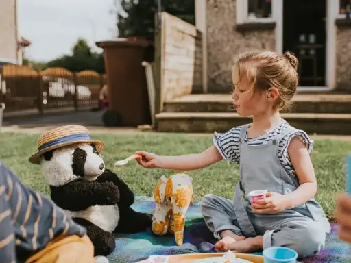 Dziewczynka karmi pluszową pandę na pikniku. Świetny sposób, co robić na nudę w ogrodzie!