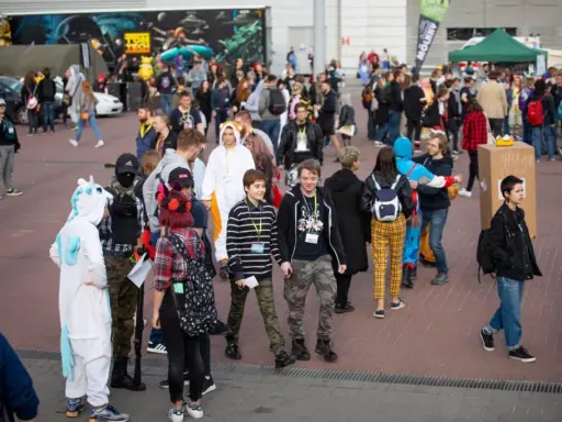 Tłum ludzi w kostiumach, w tym jednorożec i tygrys, na wydarzeniu Pyrkon. Co to za festiwal?