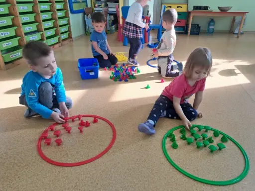 Dzieci w przedszkolu bawią się klockami, tworząc wzory w obręczach. To świetne zabawy dla 3 latka w przedszkolu.