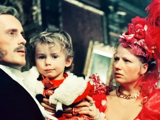 Rodzina w bogatych strojach, ojciec trzyma dziecko. Scena z filmu "Ziemia obiecana" streszczenie.