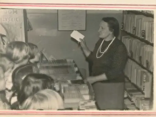 Nauczycielka w bibliotece, jak siłaczka, prezentuje dzieciom karty. Streszczenie lekcji w formie kart.