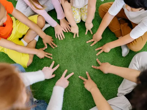 Dzieci tworzą krąg, pokazując palcami cyfry. To spokojne zabawy wyciszające Montessori, rozwijające koncentrację i współpracę.